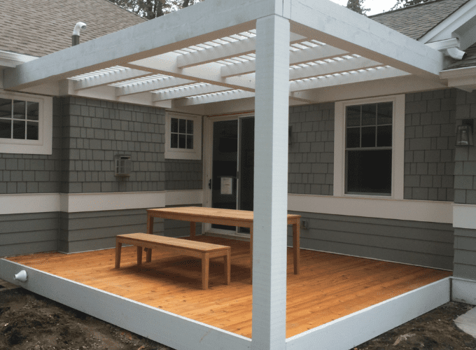 A wooden deck with benches and a pergola.