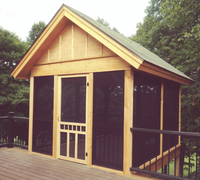 A wooden shed with a screen door on the side.