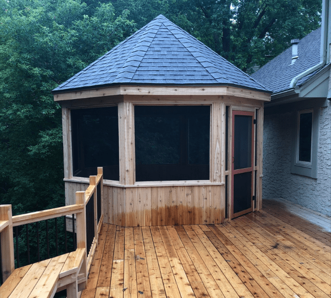 A wooden deck with a screened in porch.