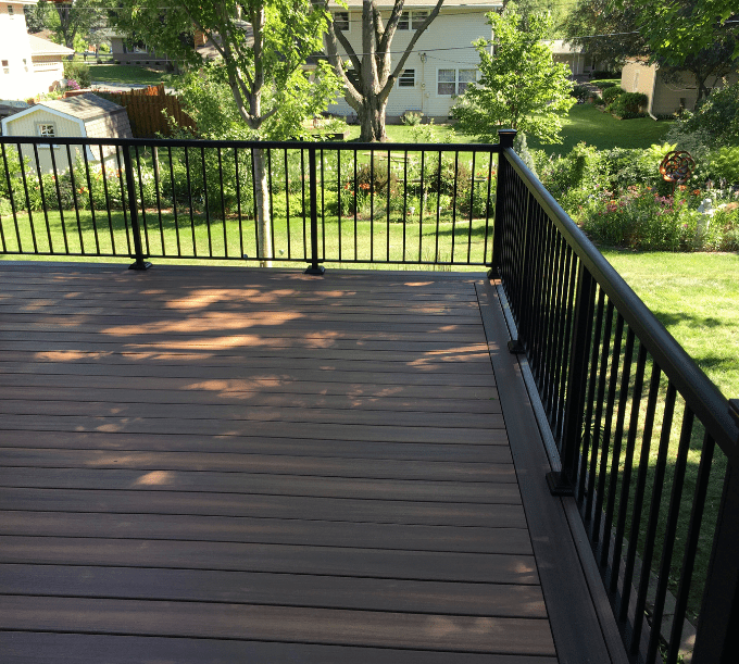 A deck with black railing and green grass.