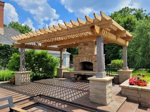 A large outdoor fireplace sitting under an arbor.