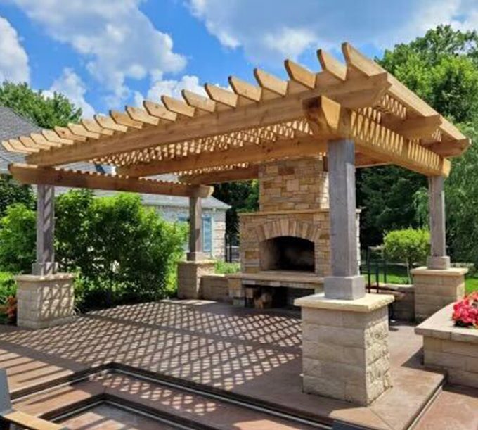 A large outdoor fireplace sitting under an arbor.