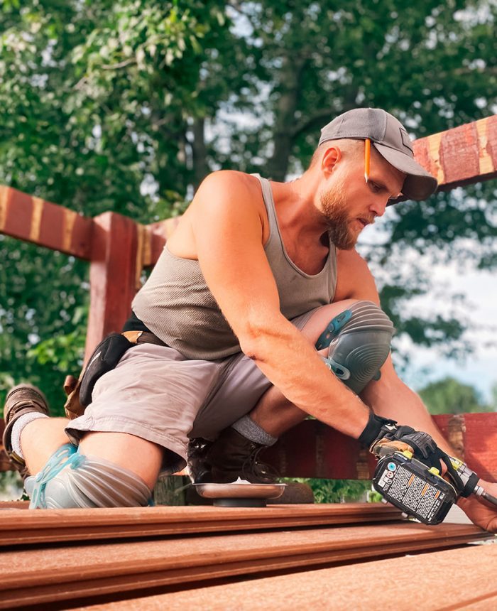 A man in grey shirt holding a black and decker drill.