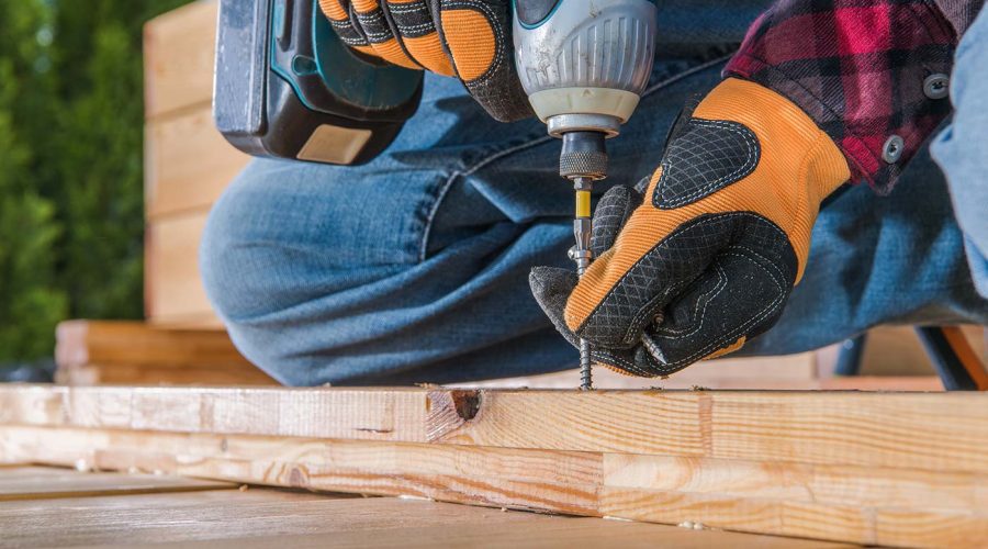 A person with orange gloves is using a drill.