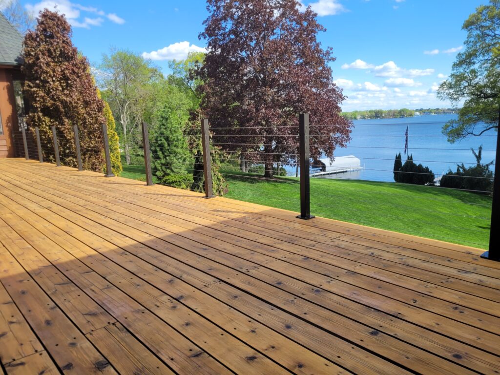 A wooden deck with trees and water in the background.