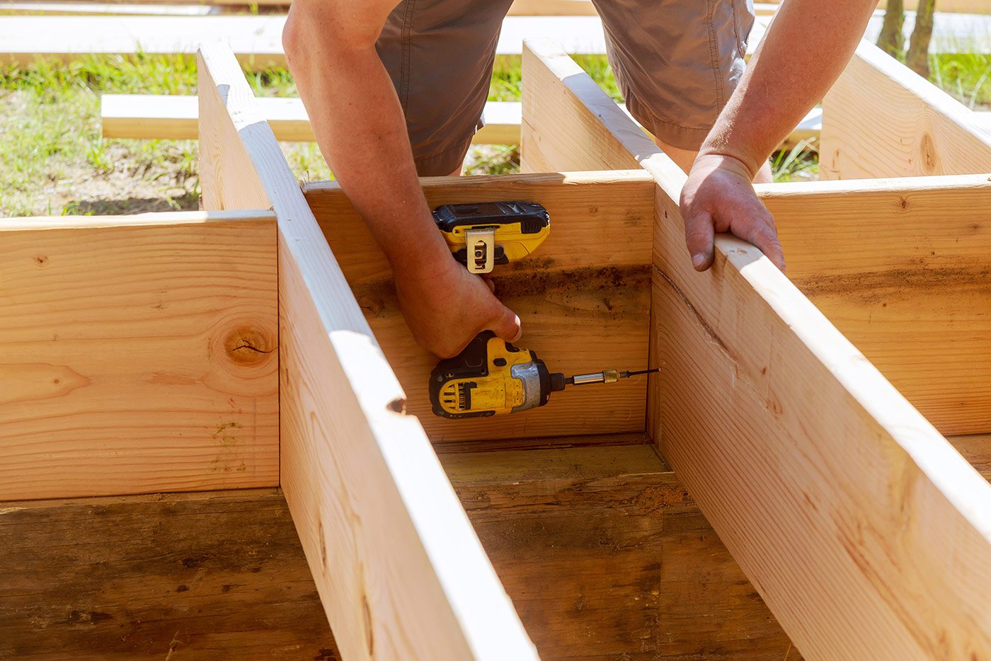 A person is using a pair of hand tools to build a wooden structure.