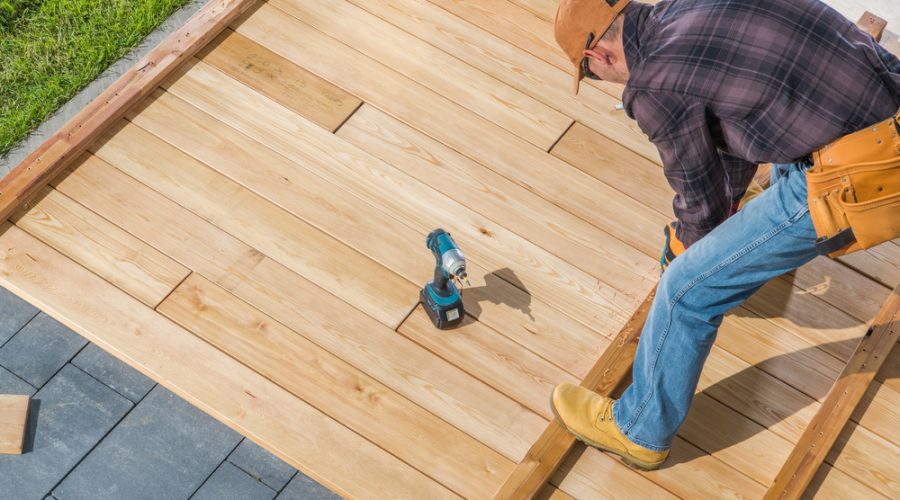 A man in yellow boots and an orange hat is on top of a wooden deck.