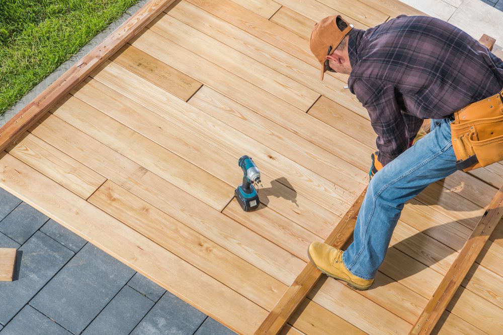 A man in yellow boots and an orange hat is on top of a wooden deck.