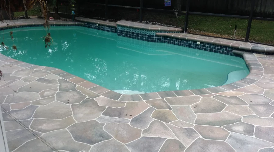 A pool with a stone floor and a tile wall.