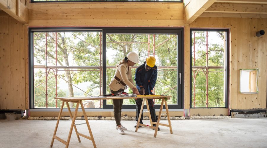 Two people working on a table in front of windows.