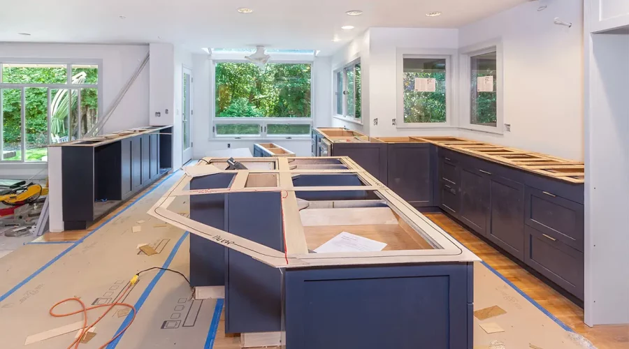 A kitchen being remodeled with blue cabinets and white counters.