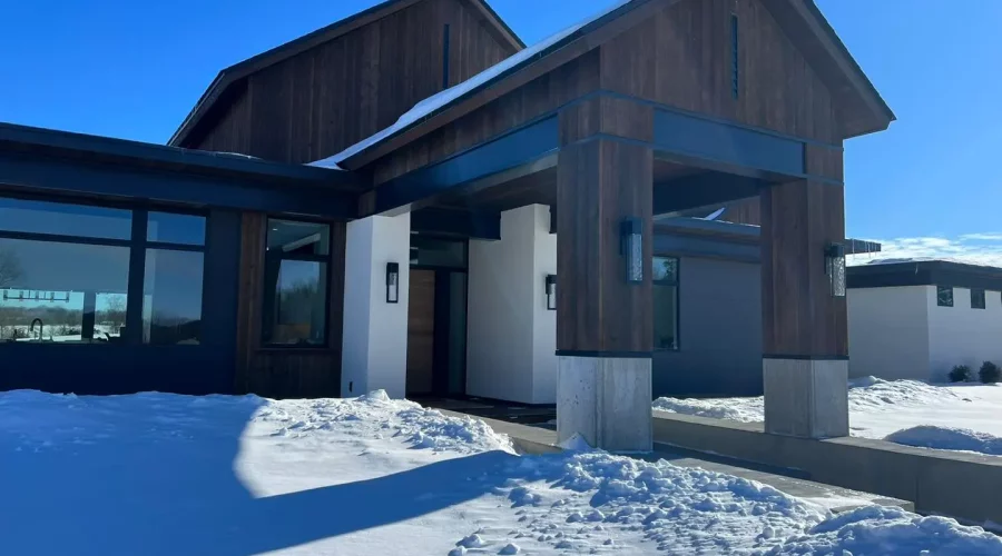 A house with snow on the ground and blue sky