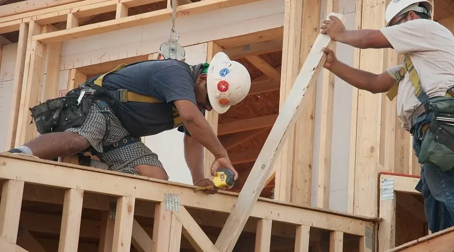 A construction worker is working on the roof of a house.