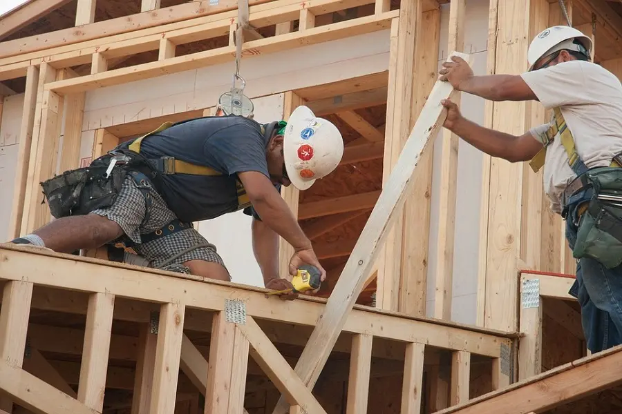 A construction worker is working on the roof of a house.