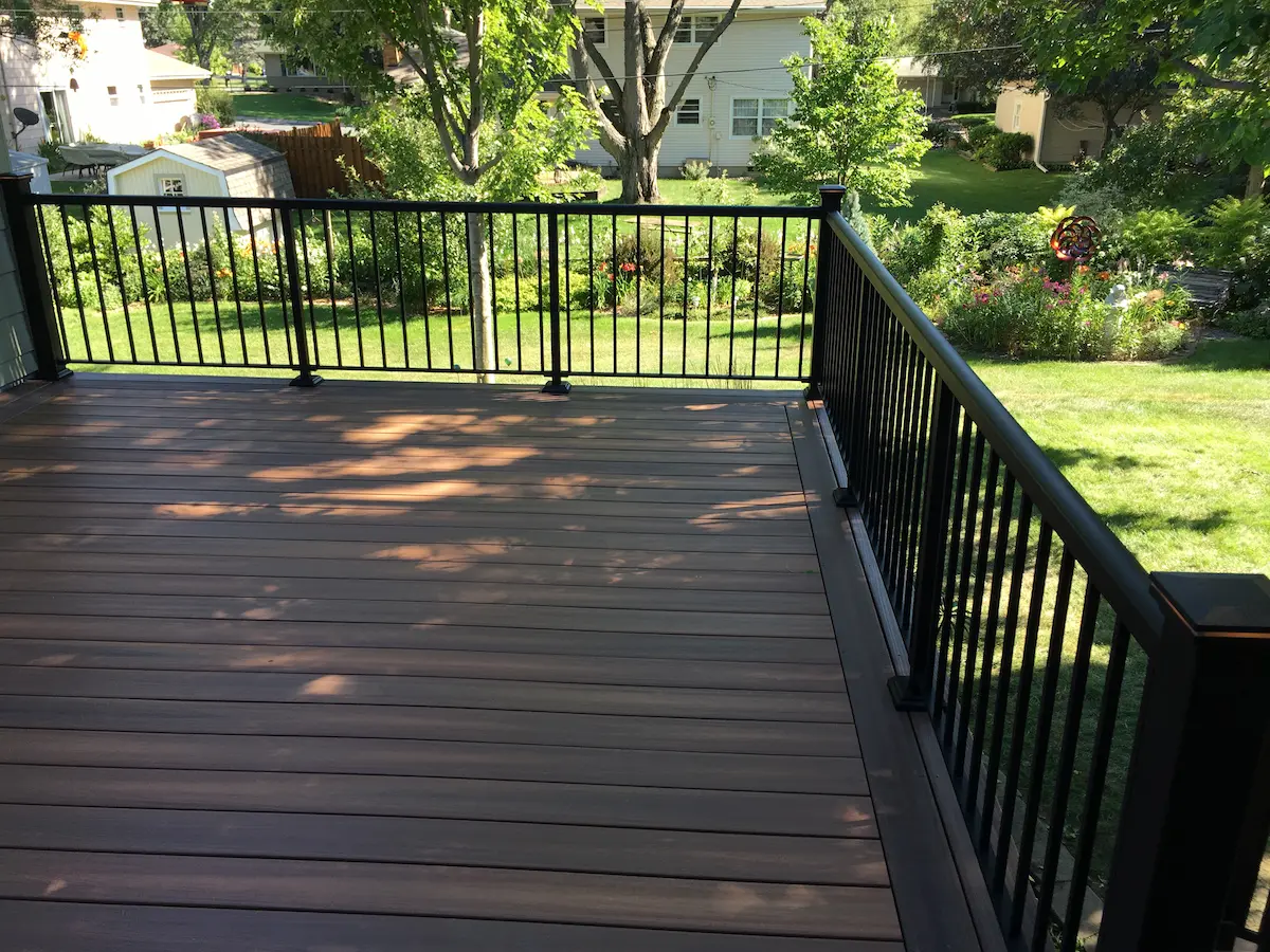 A deck with black railing and green grass.