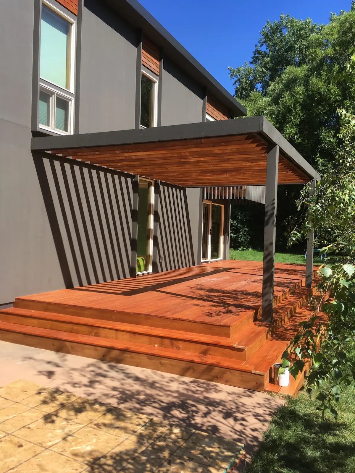 A wooden deck with steps leading to the back patio.