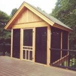 A wooden shed with black doors and windows.