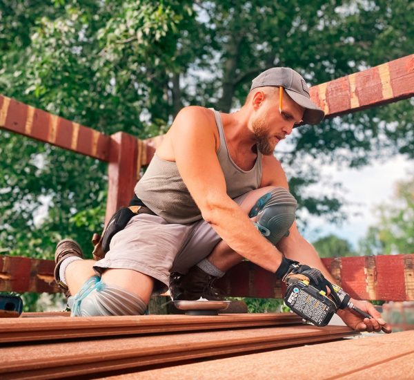 A man in grey shirt holding a black and decker drill.