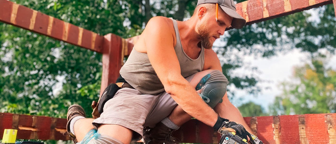 A man in grey shirt holding a black and decker drill.