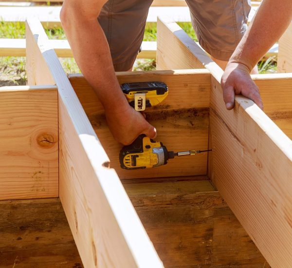 A person is using a pair of hand tools to build a wooden structure.