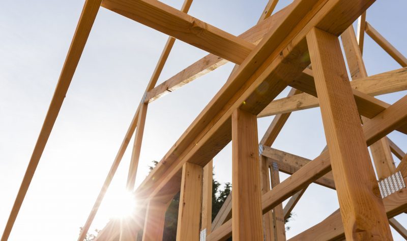 A wooden structure with beams and rafters in the sun.