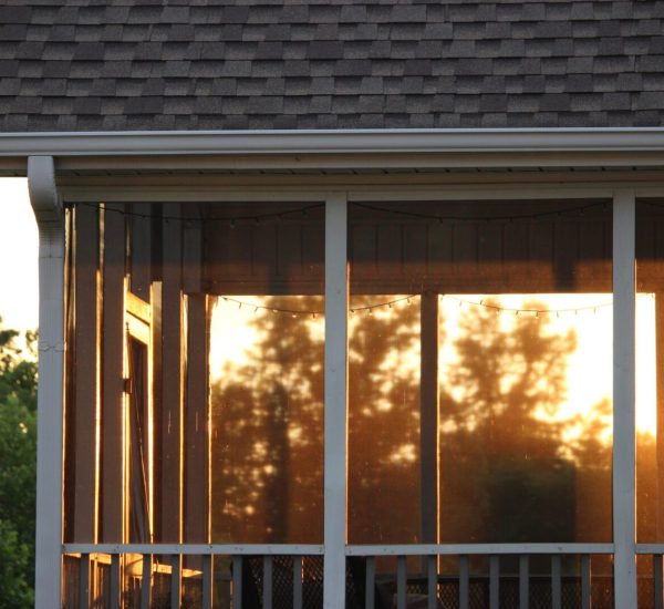 A porch with a screen door and a roof